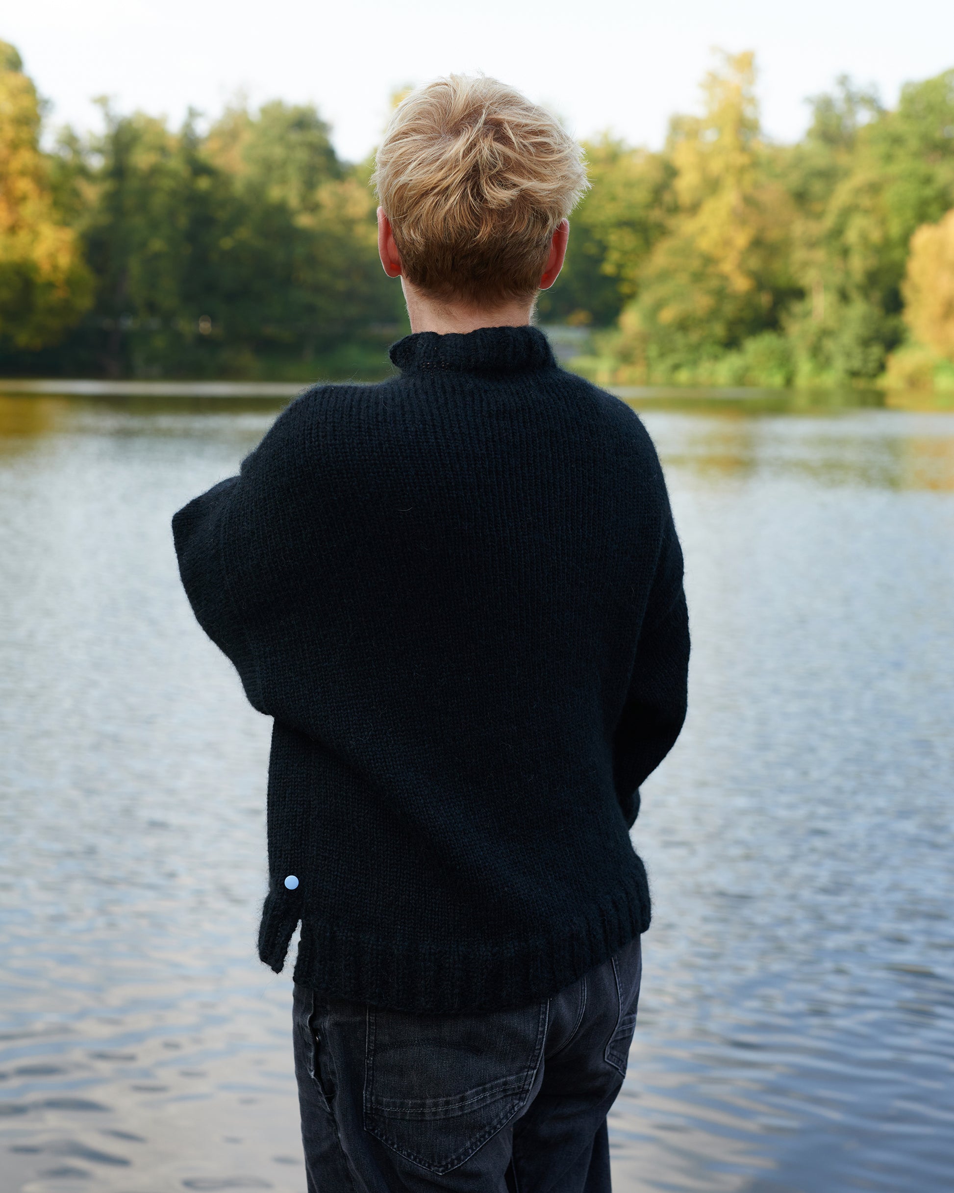 Alpaka Pullover HEIDI Rueckansicht an Model am See in der Farbe schwarz