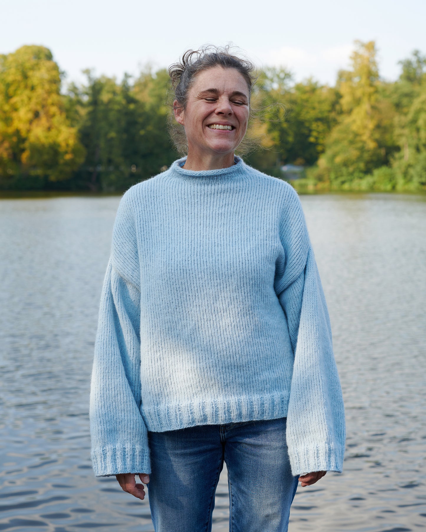 Alpaka Pullover HEIDI Vorderansicht an Model am See in der Farbe morgennebel