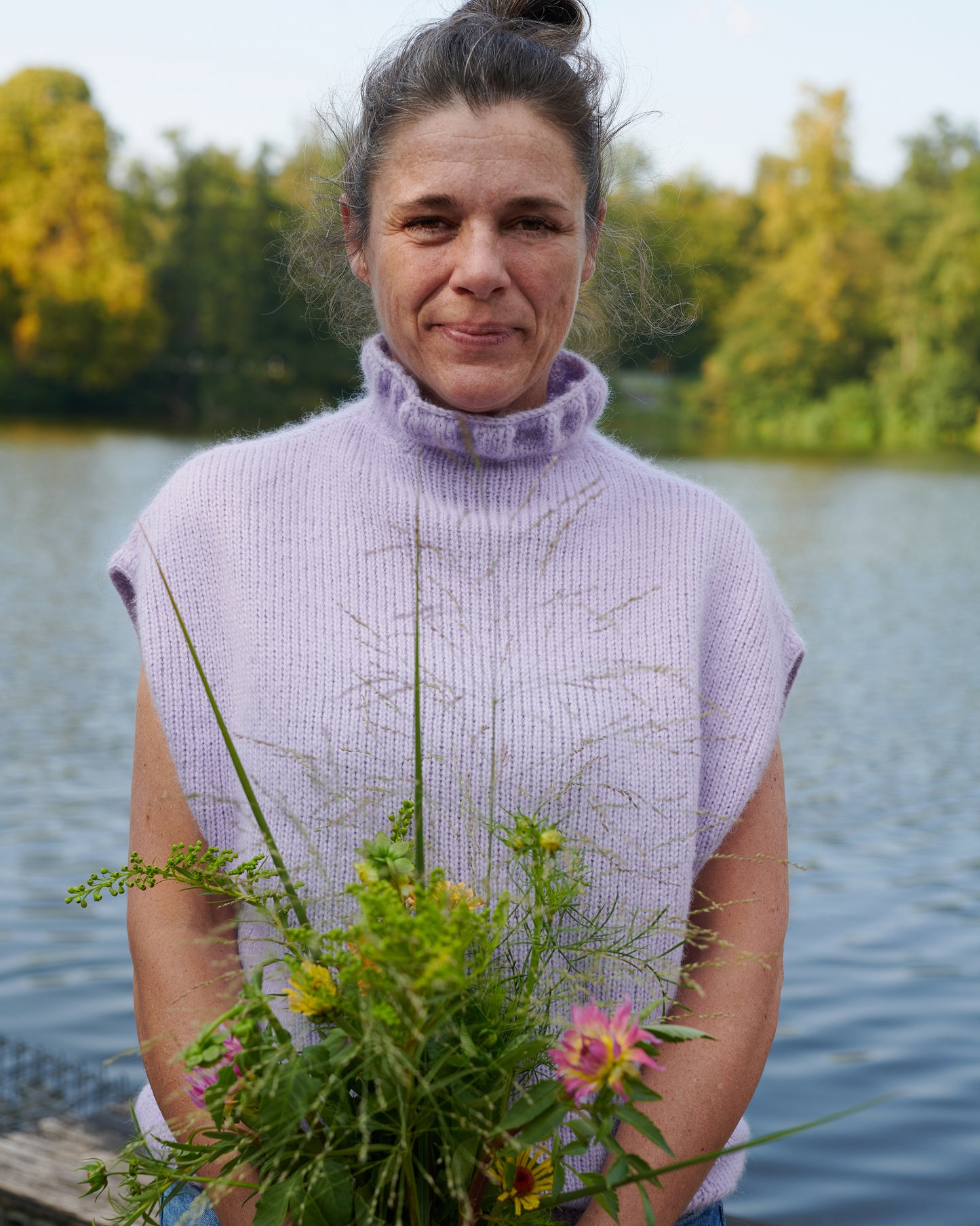 Alpaka Pullunder BELLA an Model am See mit Blumenstrauß in der Farbe orchidee