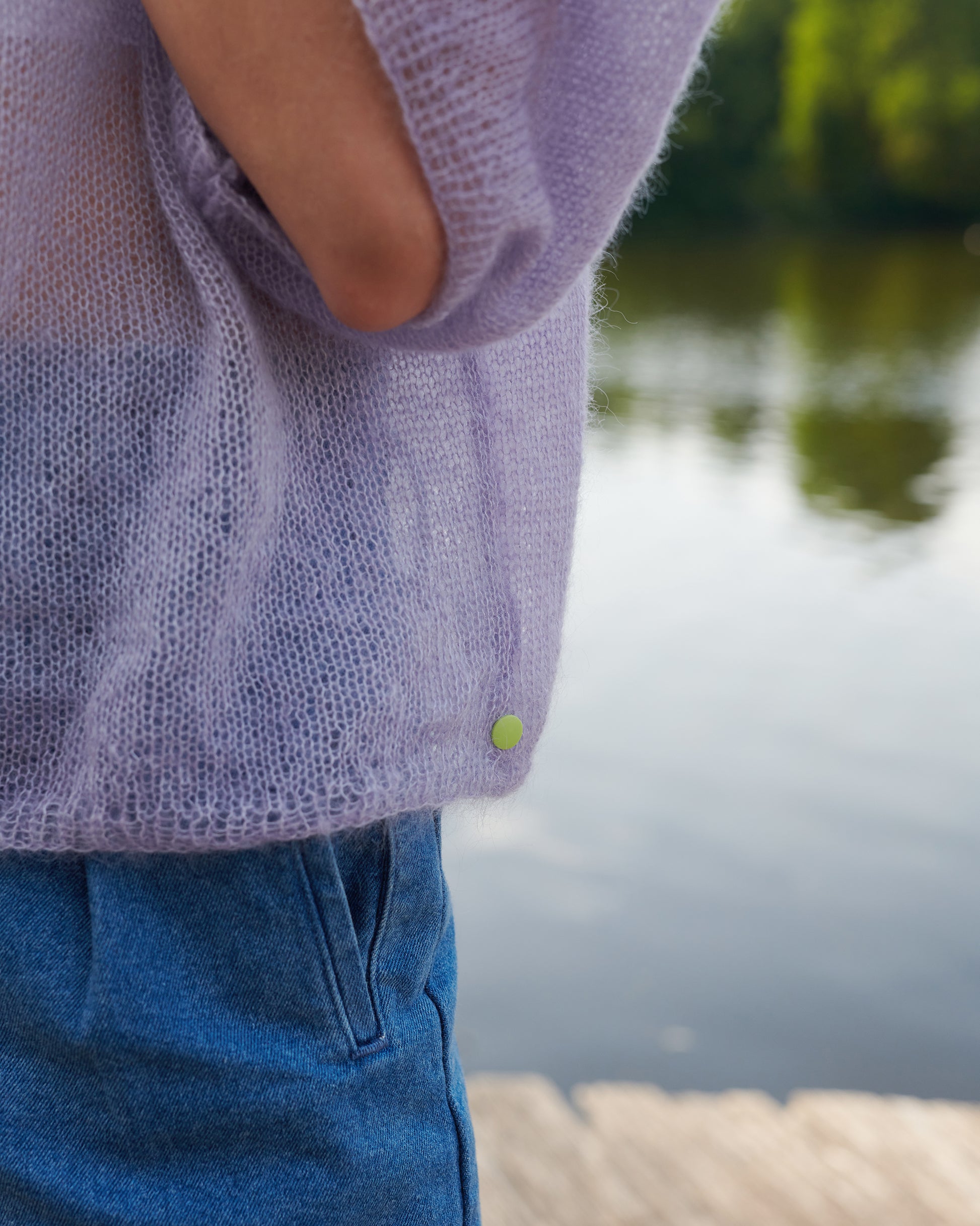 Mohair Seide Pullover FRIDA mit Rueschenkragen Detail Saumansicht mit gelbem Snap an Model  in der Farbe lila nebel.
