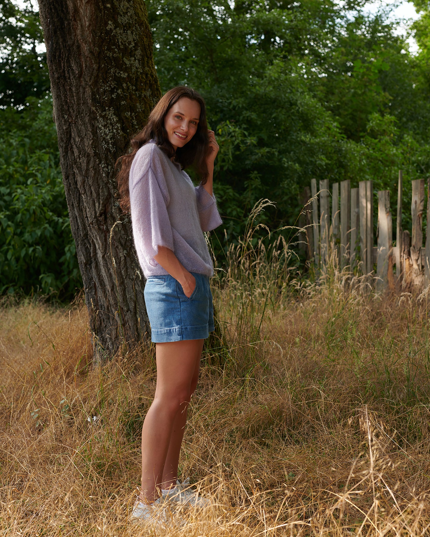 Mohair Seide Pullover FRIDA mit Rueschenkragen und Schlitz Seitenansicht an Model in Wiese in der Farbe lila nebel.