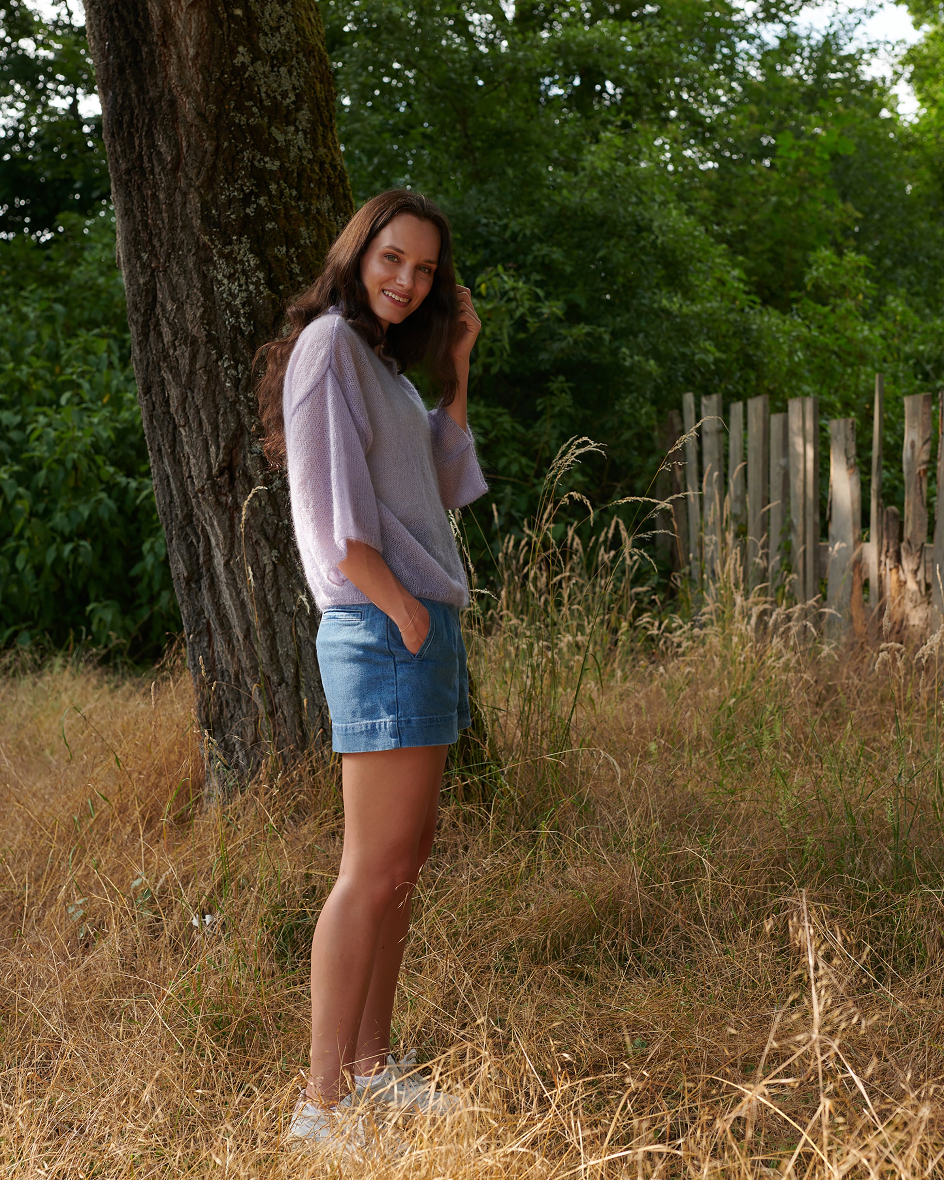 Mohair Seide Pullover FRIDA mit Rueschenkragen und Schlitz Seitenansicht an Model in Wiese in der Farbe lila nebel.